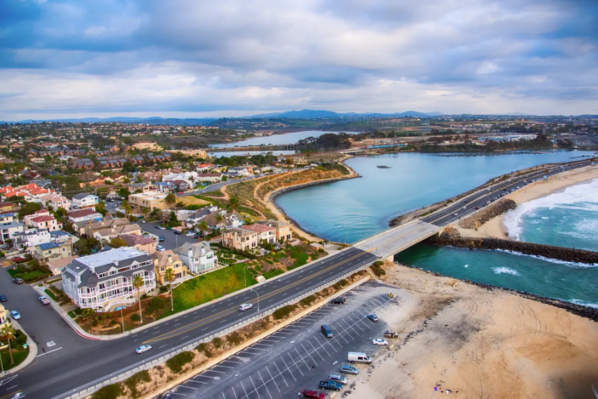 Aerial view of North San Diego County showing coastal homes, a lagoon, the beach, and inland neighborhoods and hills