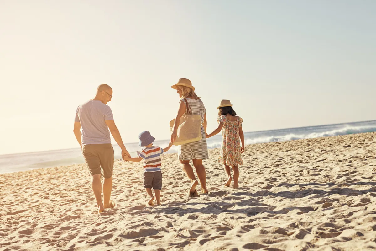 Family walking hand in hand along the sand on a sunny beach day