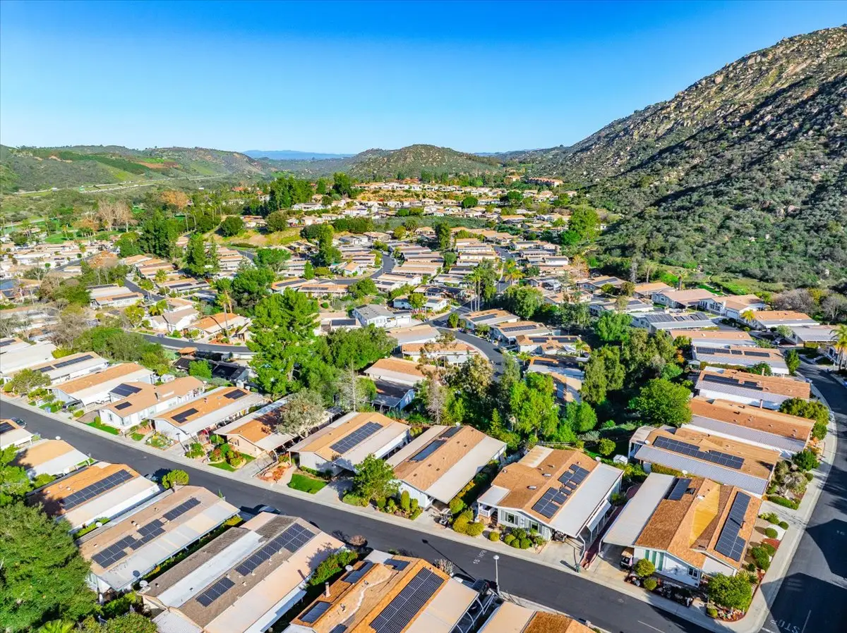 Aerial view of Champagne Village homes in Escondido, CA, with solar-paneled roofs, mature trees, and rolling hills