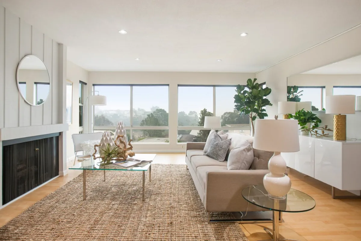 Professionally photographed living room with large windows, modern furnishings, and natural light, used to market a home for sale