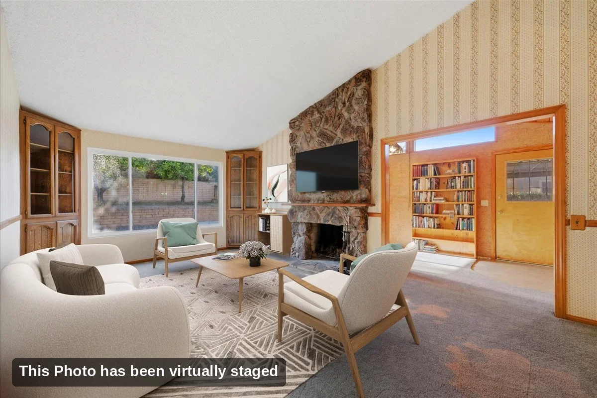 Virtually staged living room with stone fireplace, built-in display cabinets, and a large picture window in a Rancho Peñasquitos single-story home