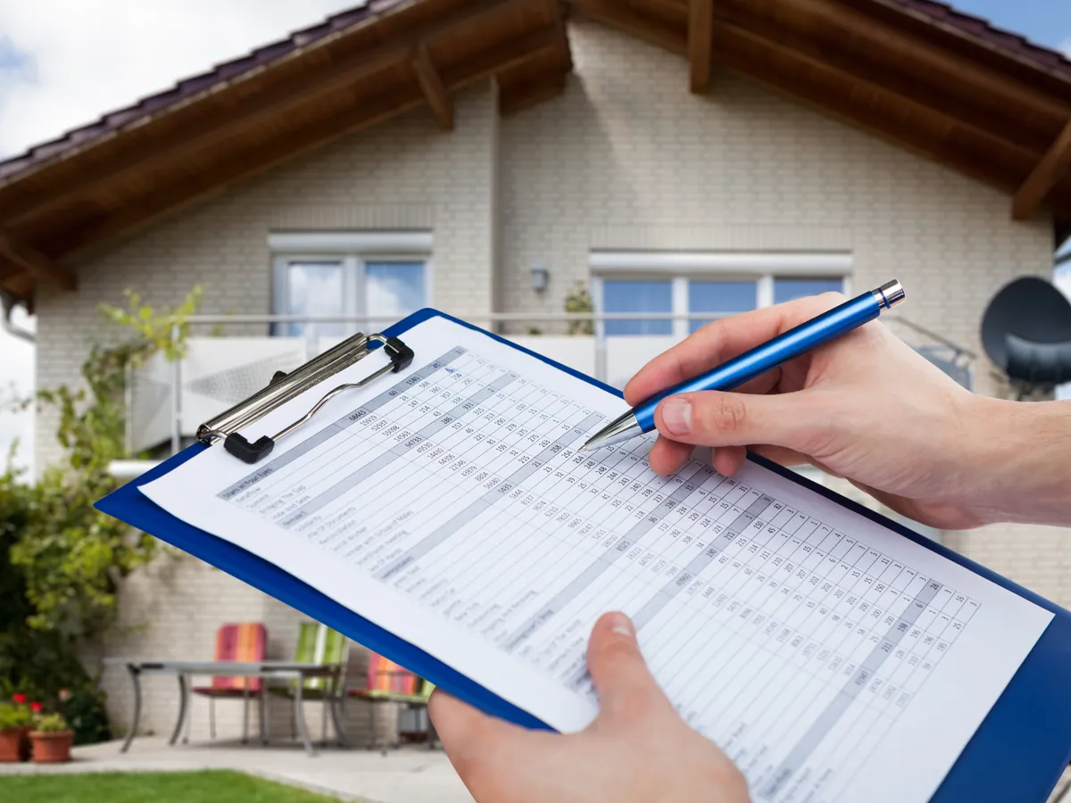 Home inspector reviewing a checklist in front of a house