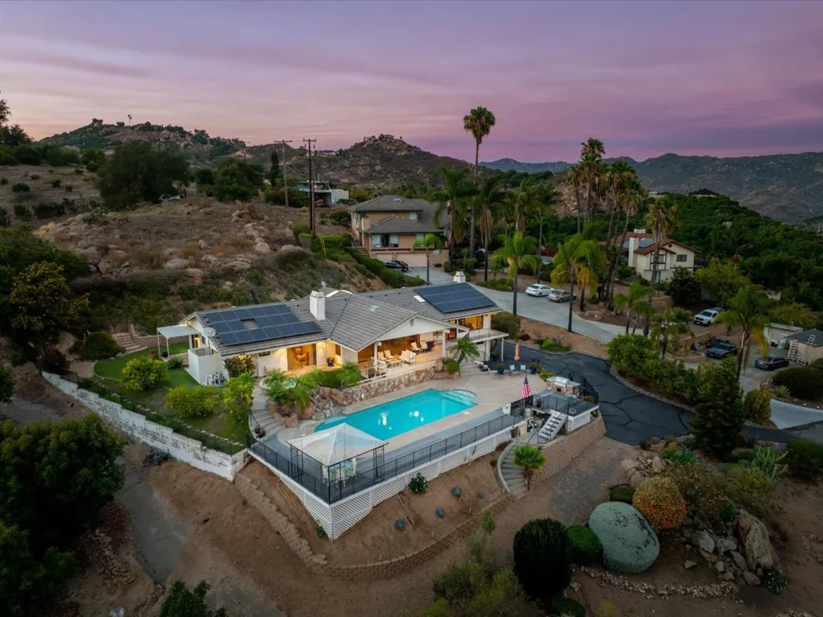 Twilight drone photo of a North County San Diego listing with a pool and mountain views