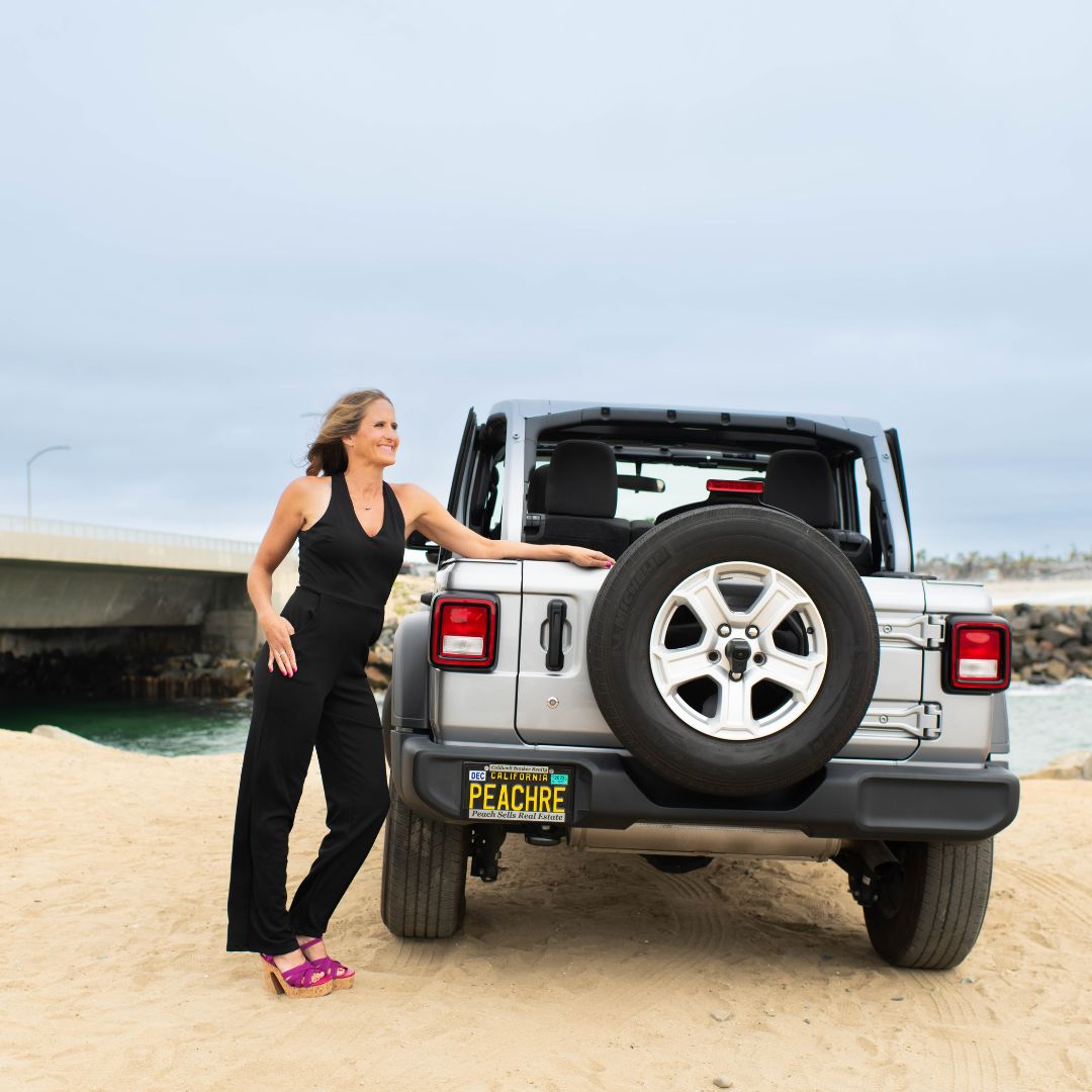 Karen Pietsch, North County San Diego REALTOR, standing beside her Jeep on the beach